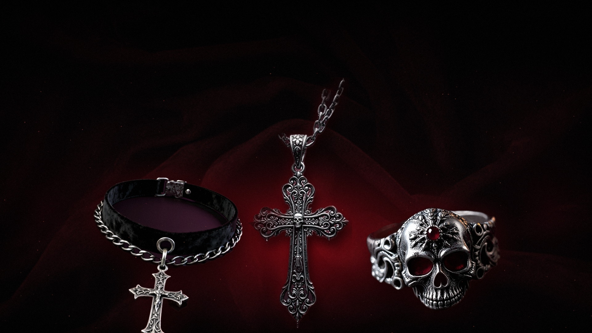The Requiem Cross necklace, Memento skull ring and Noctis choker arranged on black velvet with deep red rim light