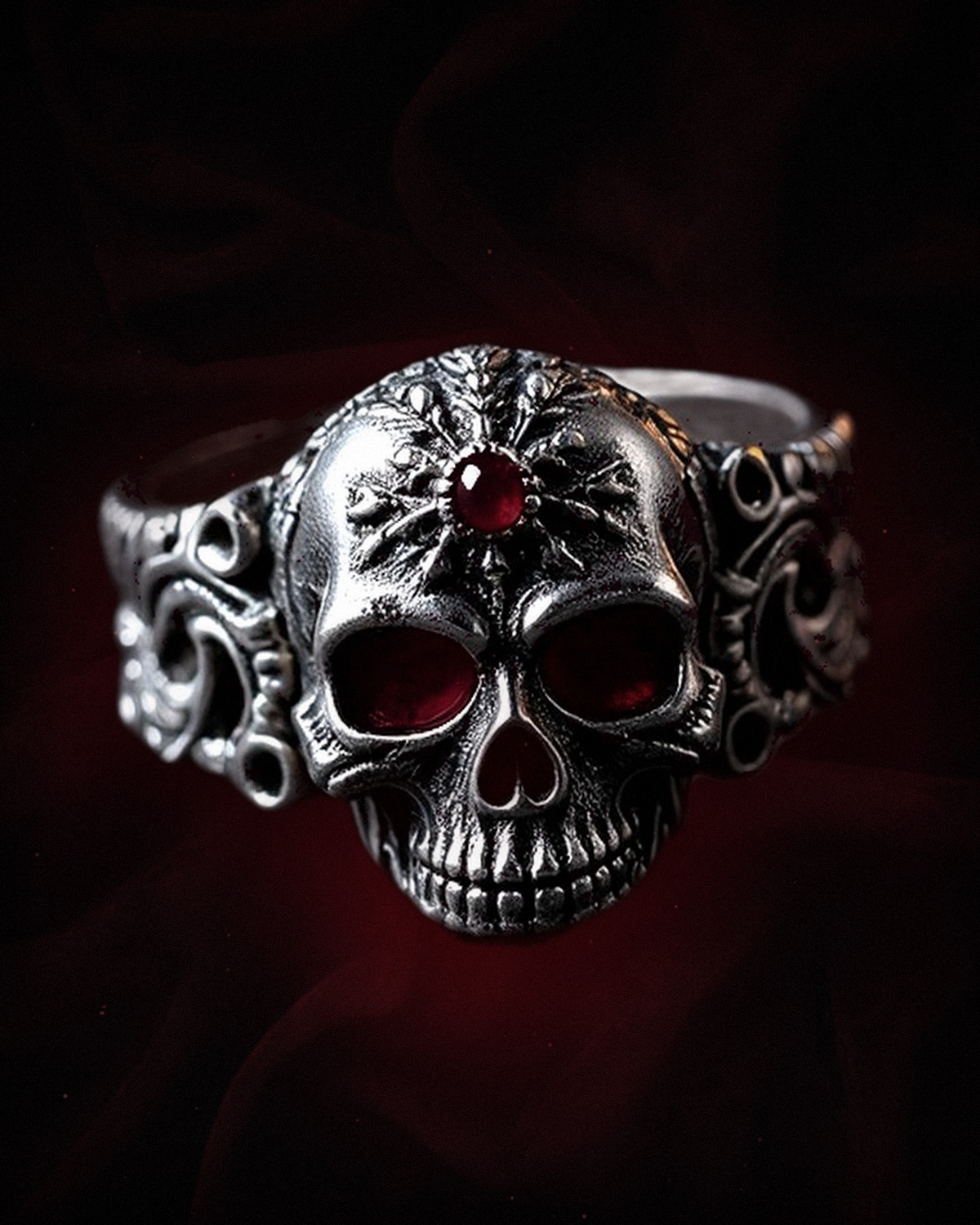 The Memento Ring — a blackened silver skull ring with lab-grown ruby eyes on deep red velvet